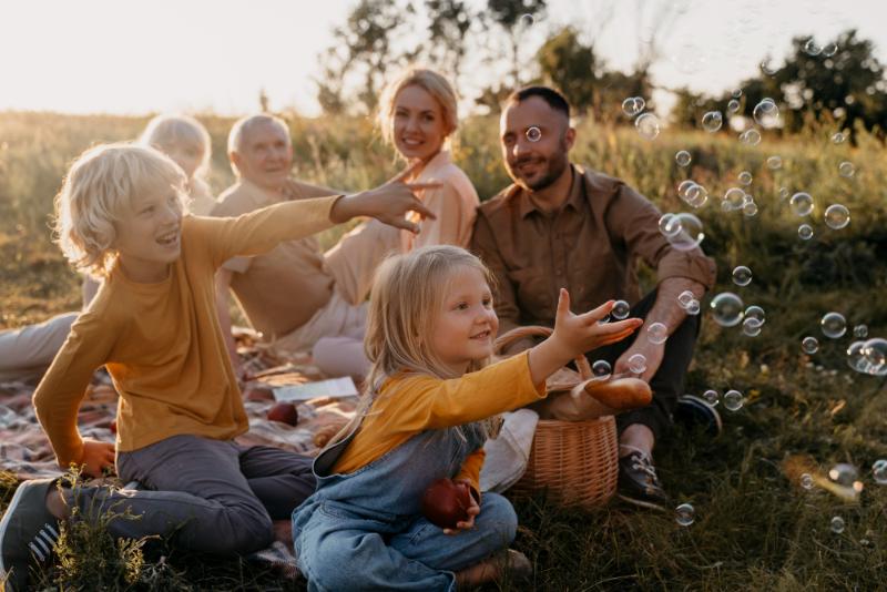 How to choose images for your website: natural lighting - a family in field having a picnic and chasing bubbles