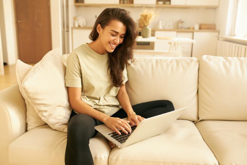 How to choose images for your website: natural color pallettes - a girl sitting on couch typing on her laptop
